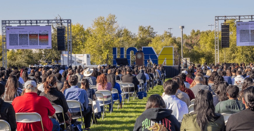 Photo depicts a crowd of students in front of a UCM letter installation on the UC Merced campus.