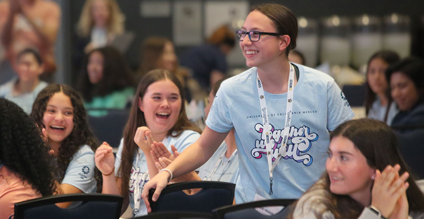 A smiling girl in a Together We Will T-shirt at the UC Mered summit for young athletes.