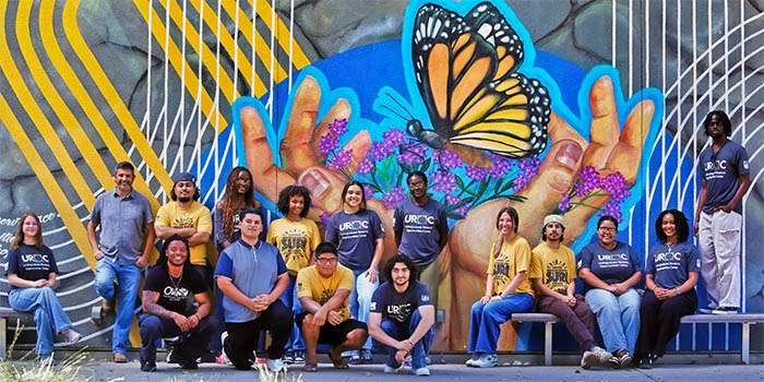 Group of students and staff in front of a mural